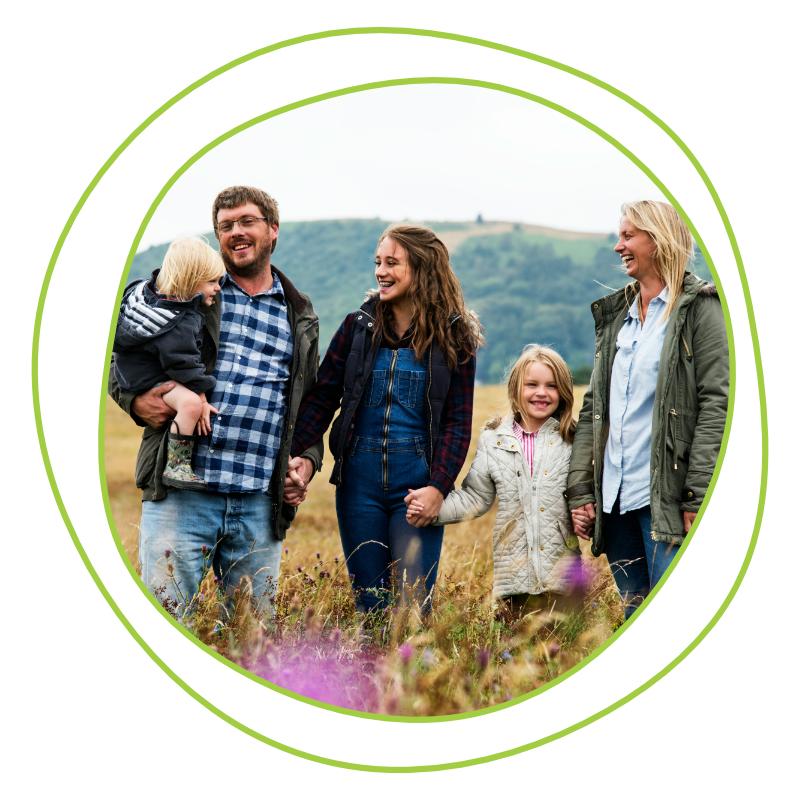 A happy family of five, holding hands and smiling in a grassy field